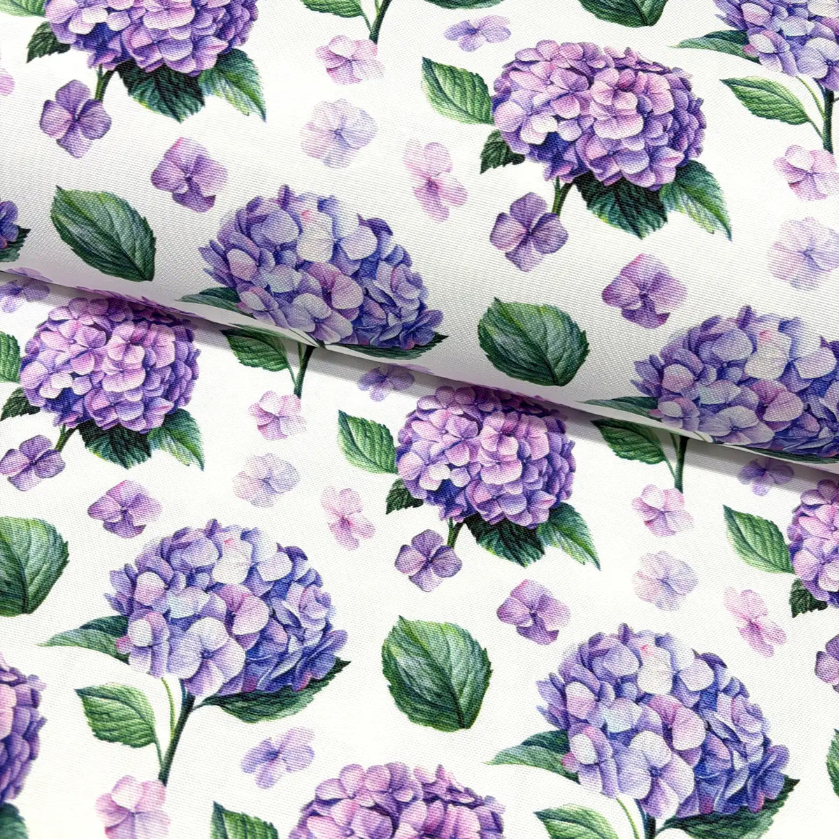 Upholstery & curtain fabric patterned with purple hydrangeas and green leaves on a white background.