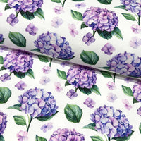 Upholstery & curtain fabric patterned with purple hydrangeas and green leaves on a white background.