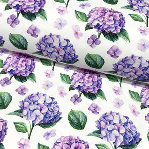 Upholstery & curtain fabric patterned with purple hydrangeas and green leaves on a white background.