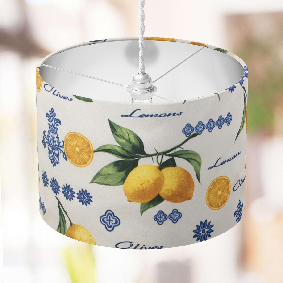 Lampshade with lemon  and olive design and text on a blurred background.