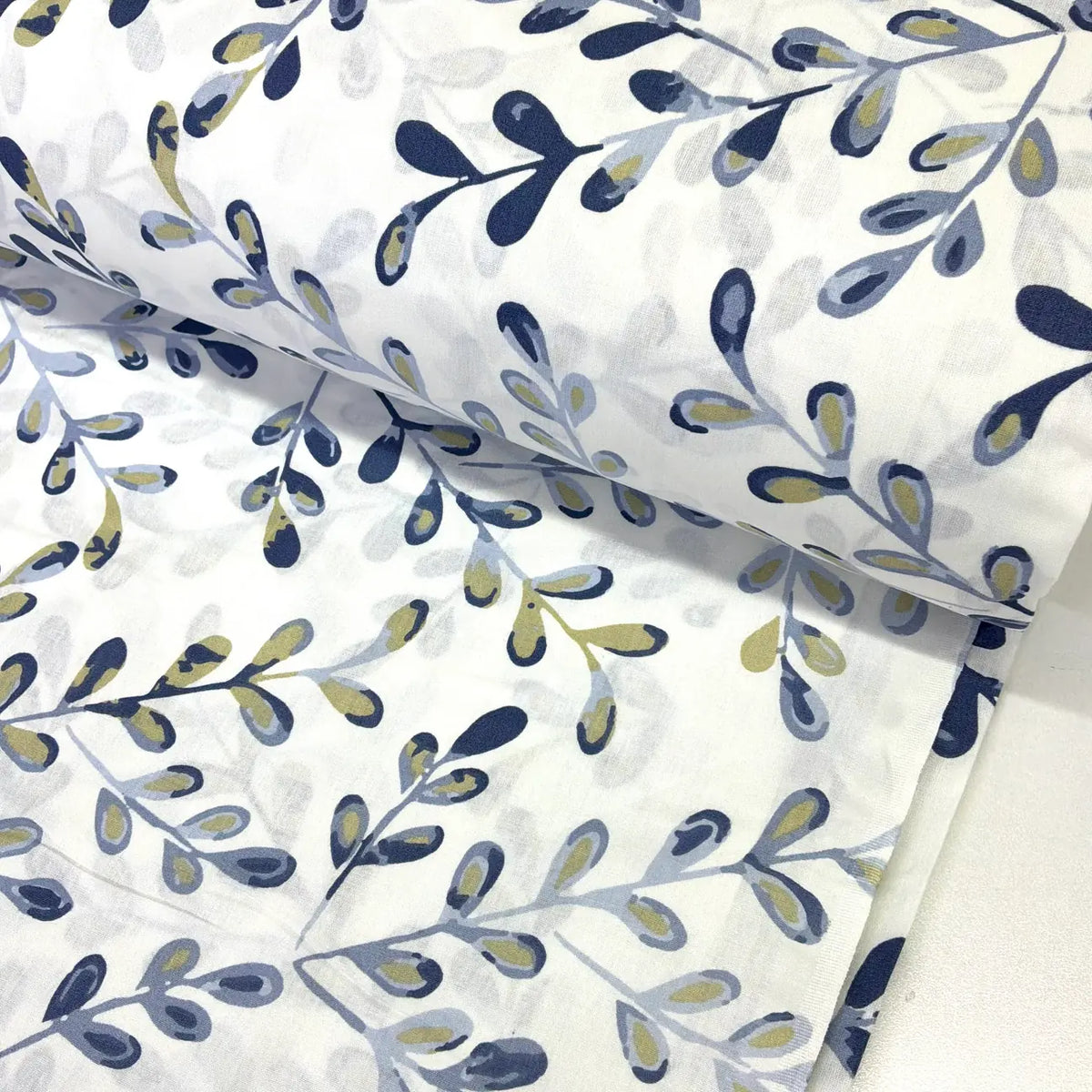 Blue and white cotton poplin fabric featuring a modern abstract leaf print in navy, grey and olive green, ideal for dressmaking, quilting and craft projects.