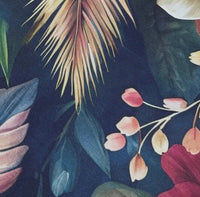 Upholstery fabric patterned with tropical leaves and flowers on a dark blue background.