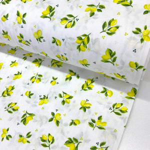 Mini lemon print cotton fabric featuring small yellow lemons and green leafy sprigs on a white background.