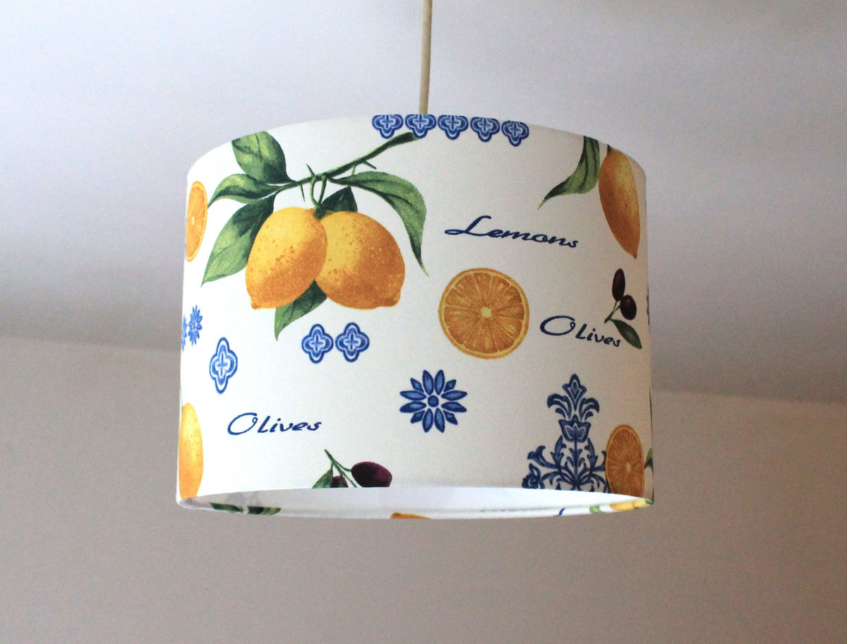 Retro lampshade with yellow lemon, green leaves, black olives and blue ornaments design on a plain background.
