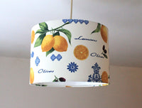 Retro lampshade with yellow lemon, green leaves, black olives and blue ornaments design on a plain background.