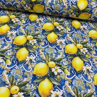Blue upholstery fabric with a pattern of yellow lemons, white flowers, green leaves and blue background.