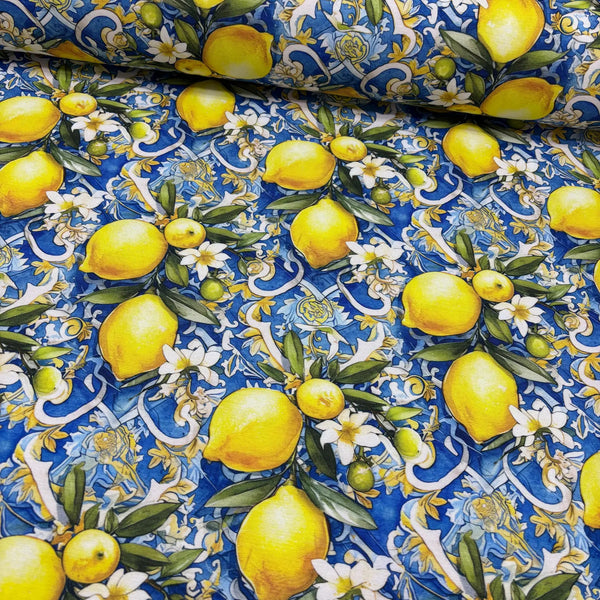 Blue upholstery fabric with a pattern of yellow lemons, white flowers, green leaves and blue background.