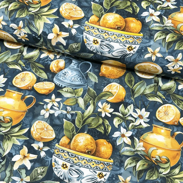 Fabric with a pattern of yellow lemons, green leaves, lemon flowers and bowls on a petrol blue background.
