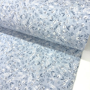 Floral patterned fabric with small white flowers on a light blue background.