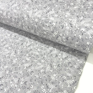 Light grey ditsy floral fabric patterned with small white flowers on a sliver grey background.