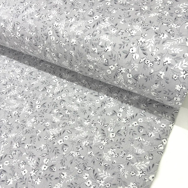 Light grey ditsy floral fabric patterned with small white flowers on a sliver grey background.