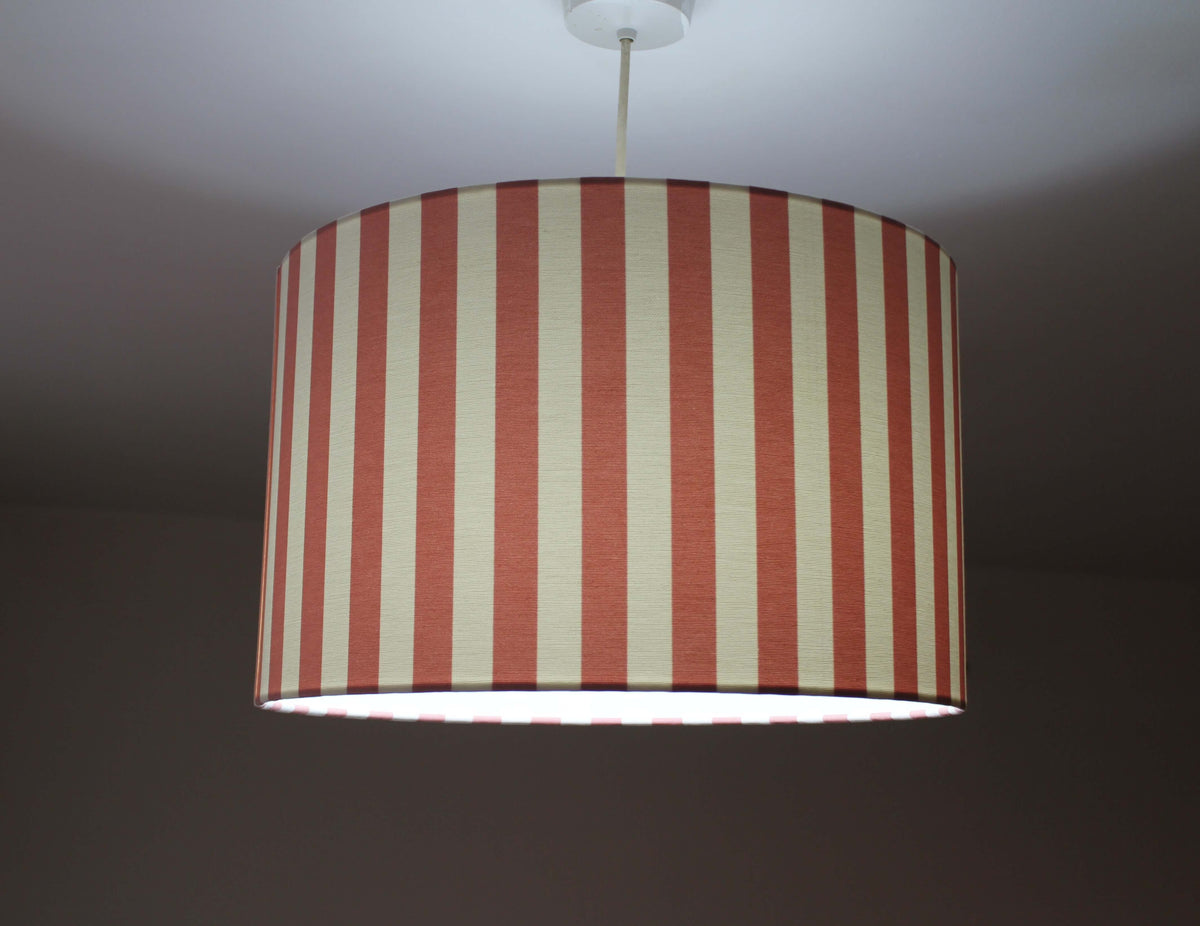 Striped lampshade with rose pink and white vertical stripes on a dark background.
