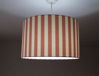 Striped lampshade with rose pink and white vertical stripes on a dark background.
