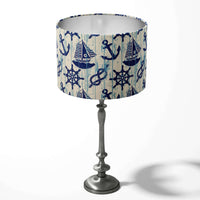 Blue and white table drum lampshade with a nautical coastal theme on a white background.