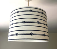Nautical striped ceiling lampshade with rope knot design on a plain background.