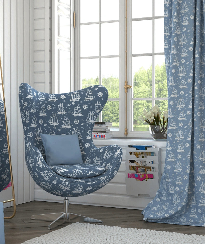Blue and white nautical and marine patterned chair and curtain in a room with large windows.