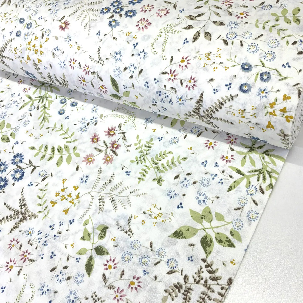 Meadow flower cotton poplin fabric with a botanical floral print featuring blue, pink and mustard flowers on a white background.