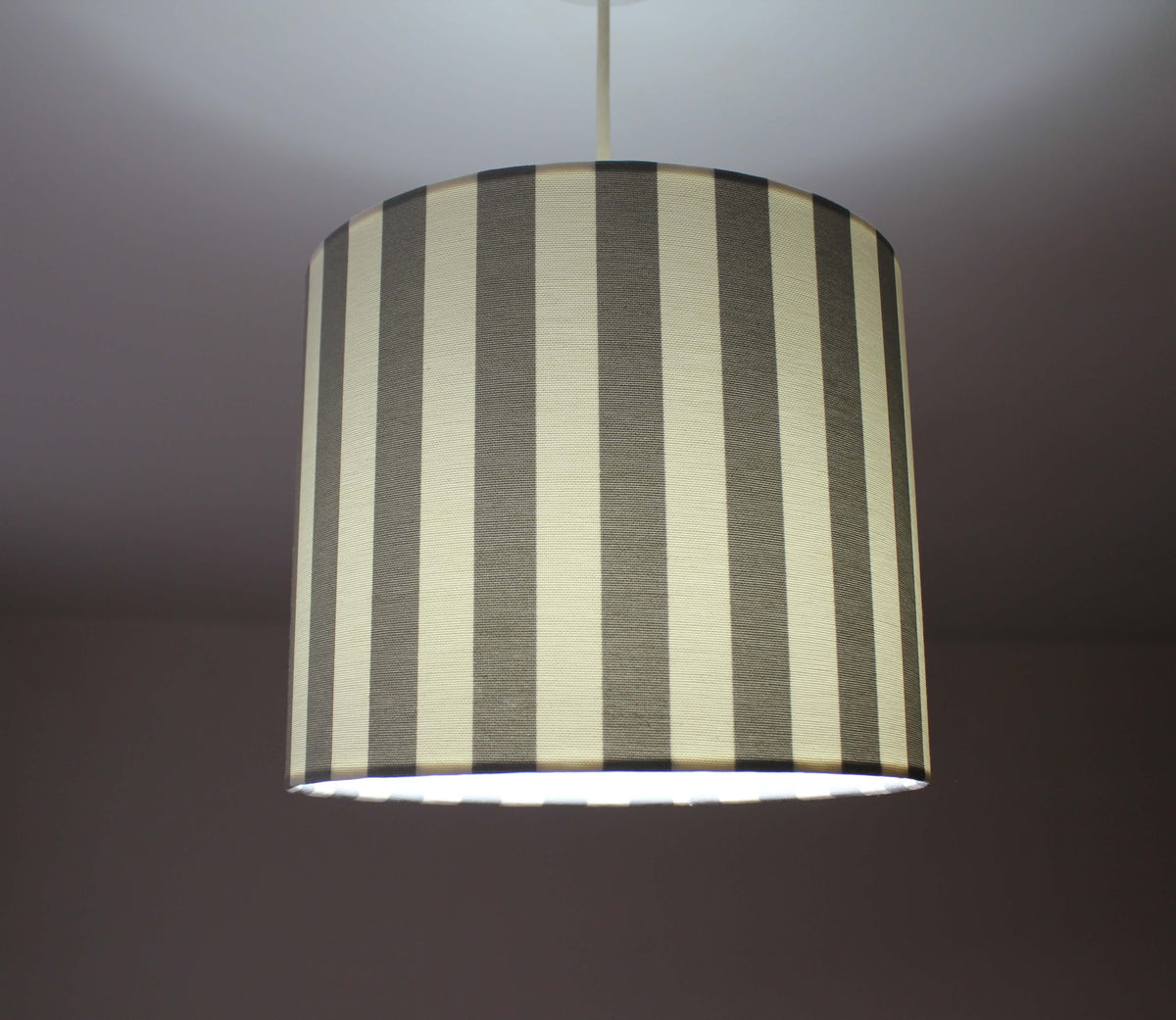 Striped lampshade with a grey and white pattern on a plain background.