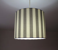 Striped lampshade with a grey and white pattern on a plain background.