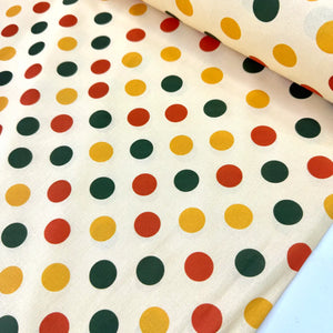 Multicolour polka dot cotton fabric featuring red, yellow and green spots on a cream backgroundç