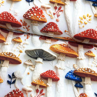 Embroidered mushrooms and toadstools in red, mustard, orange and blue printed on a white upholstery fabric.