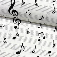Close-up of black & white music notes patterned upholstery fabric.
