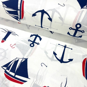 Cotton poplin fabric with nautical patterns including anchors and sailboats on a white background.
