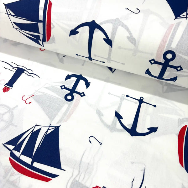 Cotton poplin fabric with nautical patterns including anchors and sailboats on a white background.