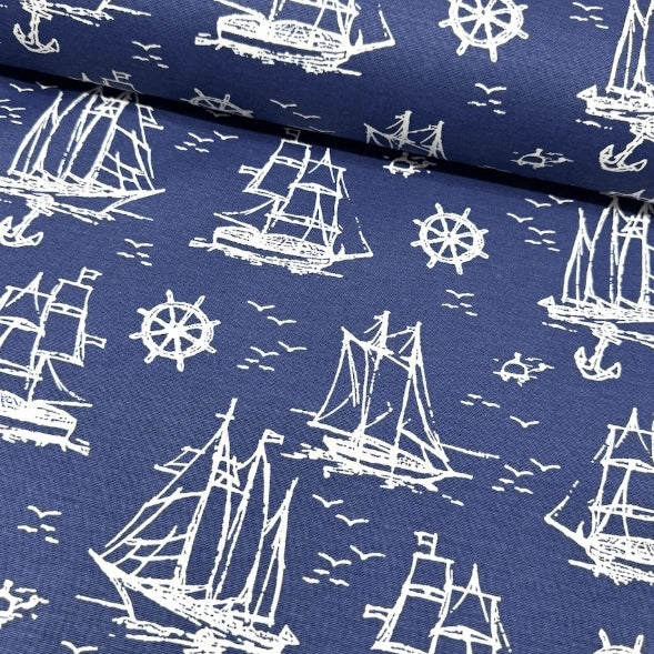 Nautical pattern upholstery fabric with white ships and wheels on a navy blue background.