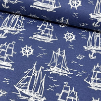 Nautical pattern upholstery fabric with white ships and wheels on a navy blue background.