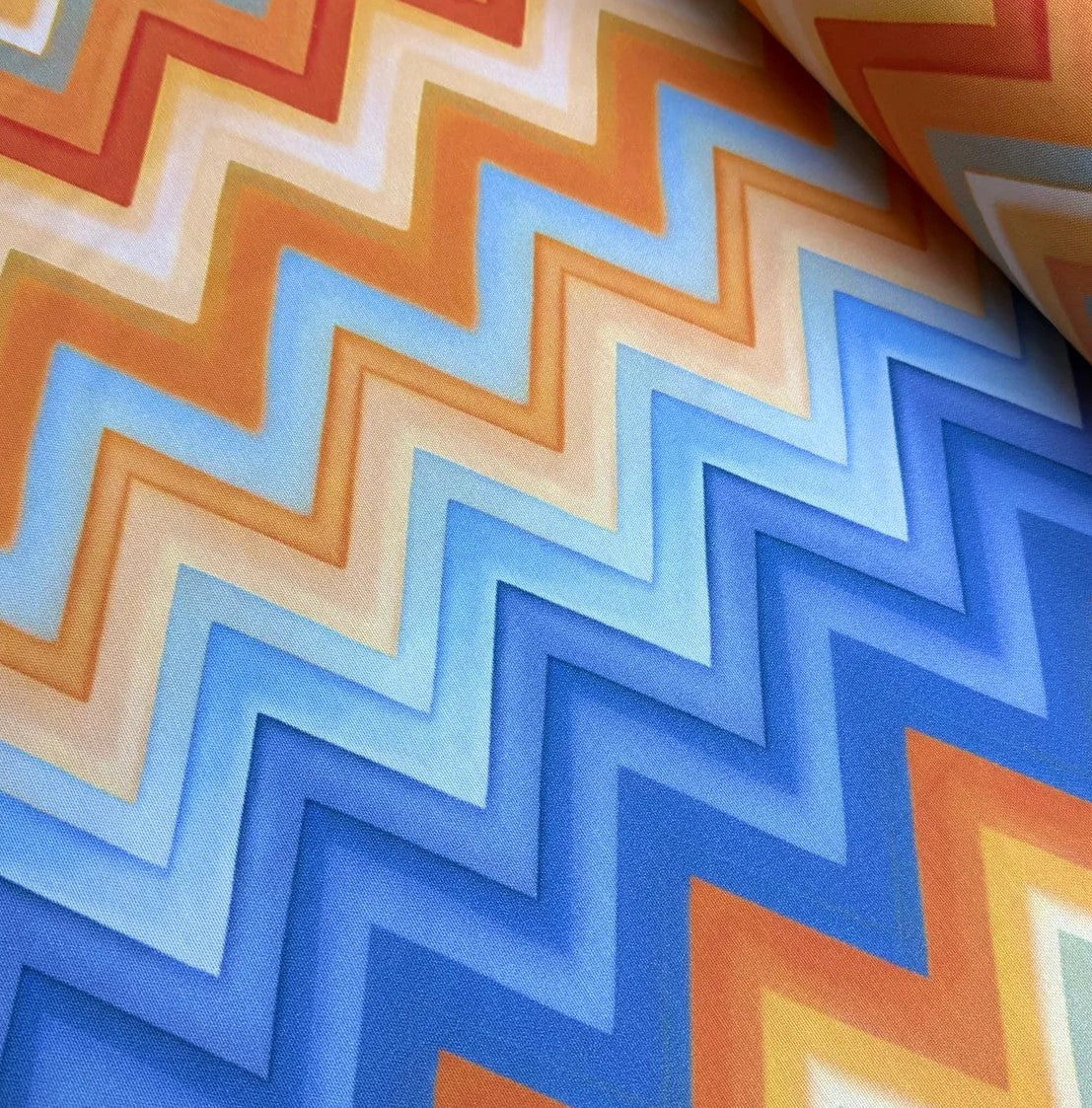 Close-up of upholstery curtain fabric with orange and blue chevron pattern.