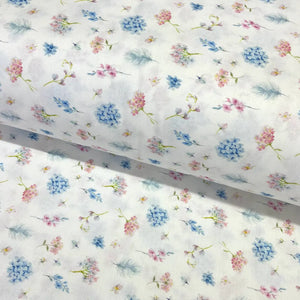 Pastel ditsy floral cotton fabric featuring delicate blue and pink flowers with botanical sprigs on a white background.