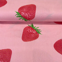 Cotton poplin fabric featuring large realistic red strawberries on a soft pink background, ideal for dressmaking, quilting and craft projects.