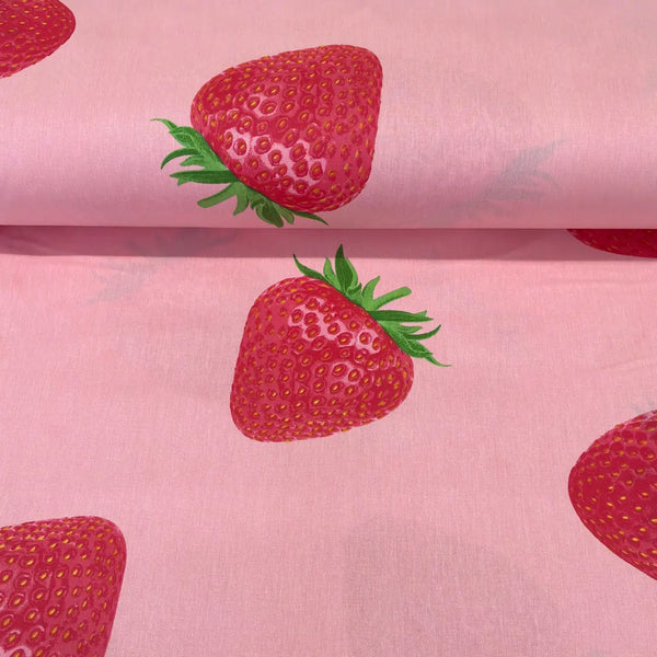Cotton poplin fabric featuring large realistic red strawberries on a soft pink background, ideal for dressmaking, quilting and craft projects.