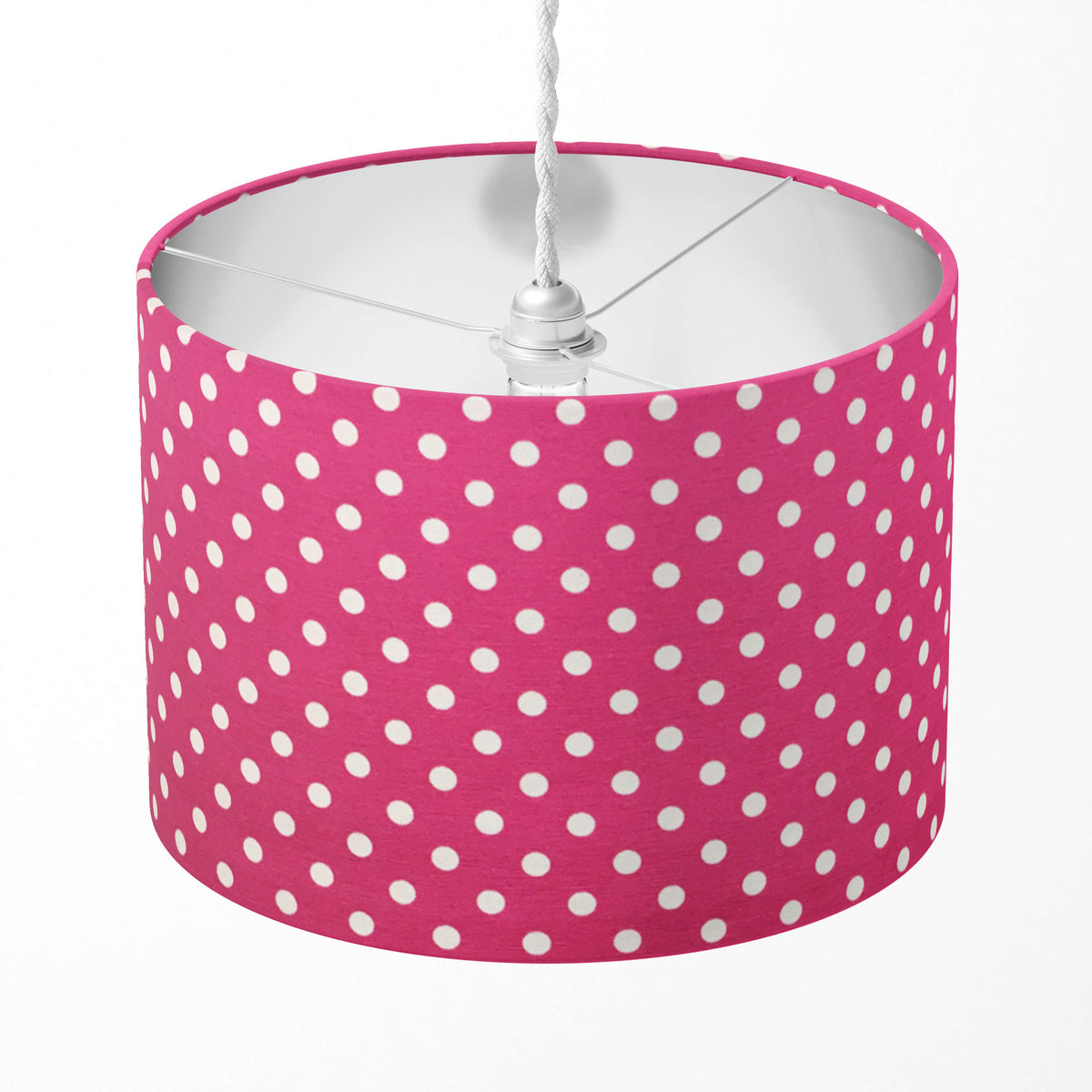 Pink lampshade with white polka dots on a white background.