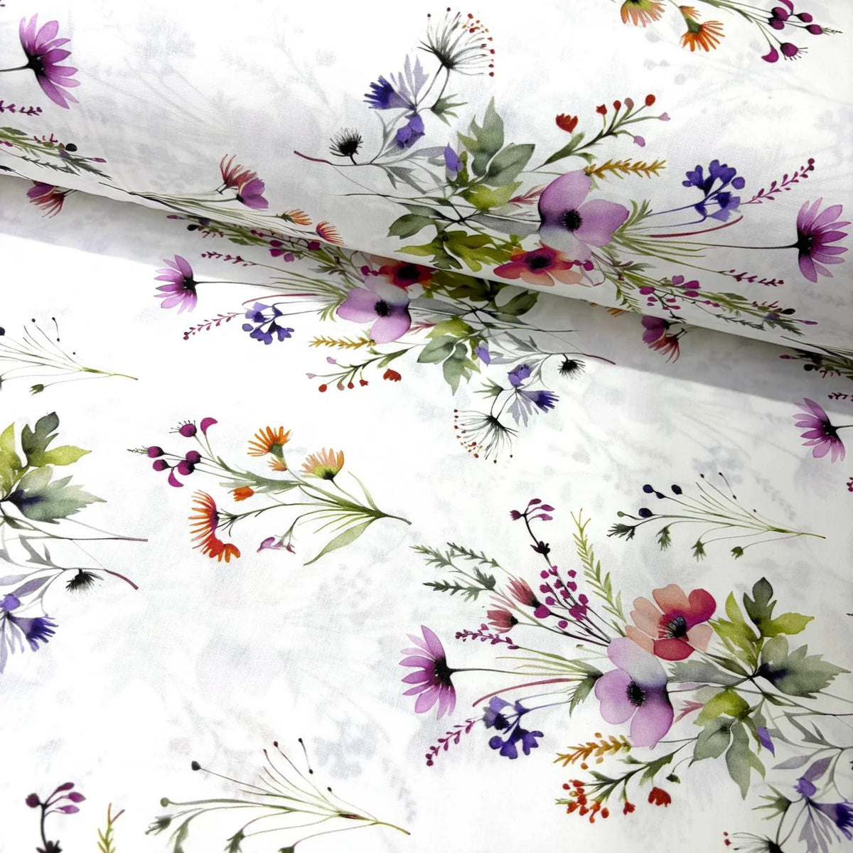 White cotton poplin fabric with a delicate watercolor floral print featuring purple, pink, coral, and green wildflowers.