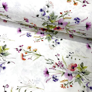 White cotton poplin fabric with a delicate watercolor floral print featuring purple, pink, coral, and green wildflowers.