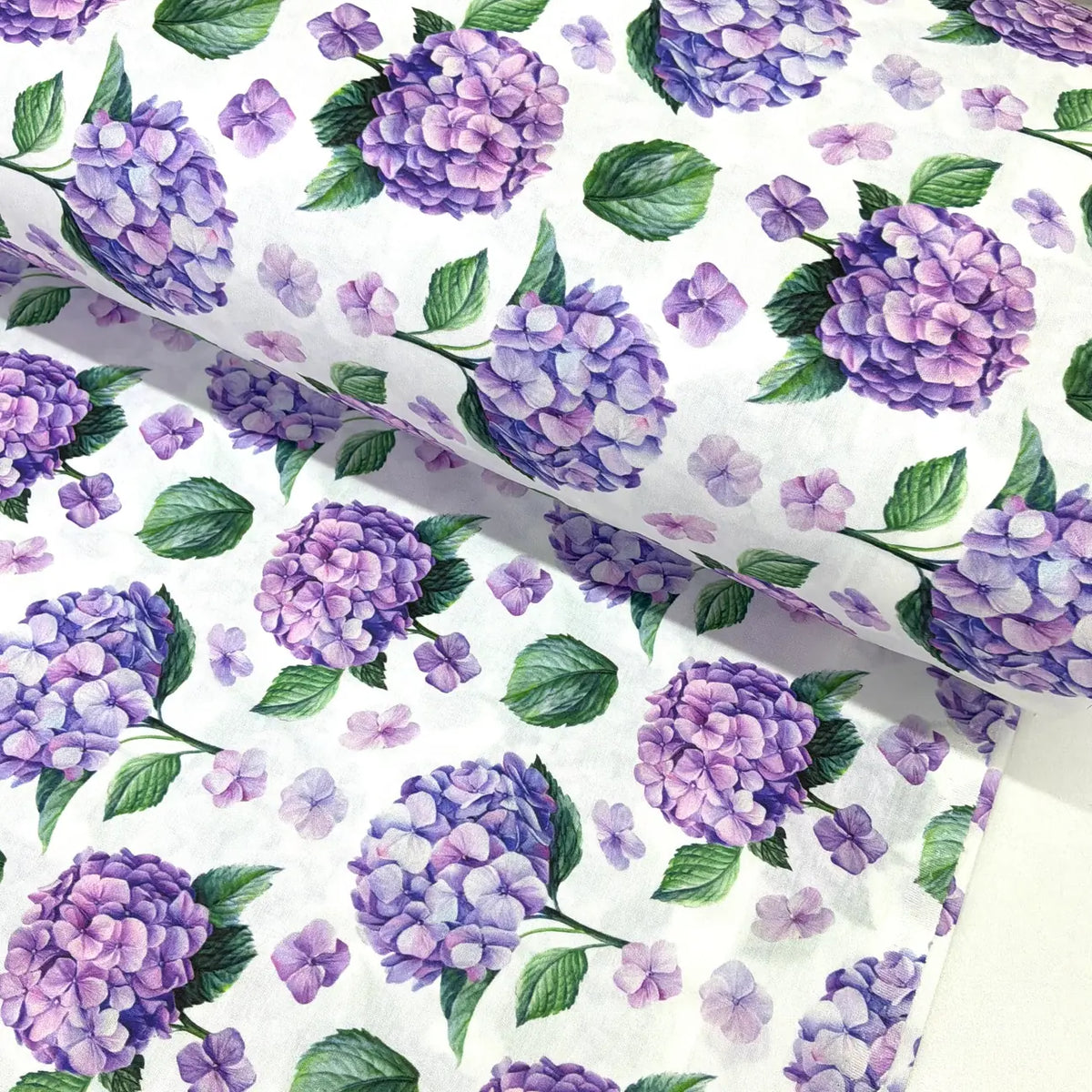 Purple hydrangea cotton poplin fabric featuring lilac and lavender floral blooms with green leaves on a white background.
