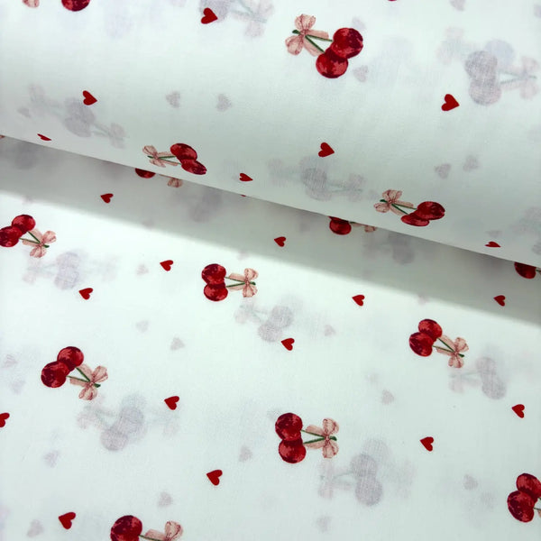 Cotton poplin fabric with red cherry and heart pattern on a white background.