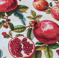 Upholstery fabric patterned with red pomegranates and green leaves on a light background.