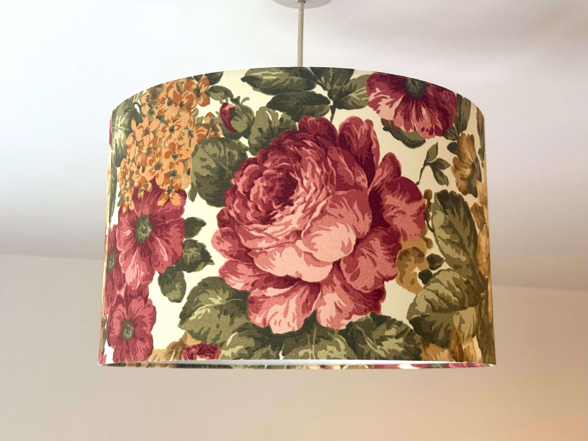 Burgundy cabbage rose and sage green leaves print ceiling lampshade on a plain background.