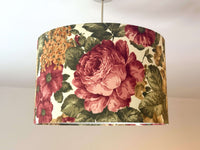 Burgundy cabbage rose and sage green leaves print ceiling lampshade on a plain background.