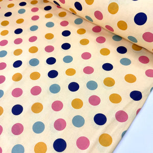 Multicoloured retro polka dot cotton fabric featuring pink, navy, mustard yellow and pastel blue spots on a cream background.