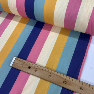 Retro rainbow cotton stripe fabric with large vertical stripes in pink, mustard yellow, navy blue, pastel blue and cream.