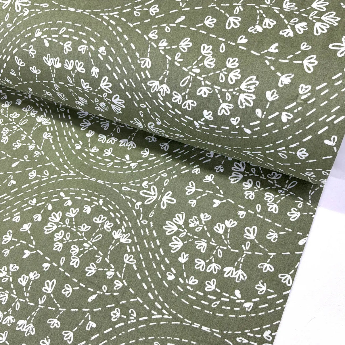 Sage green floral fabric featuring a white floral vine and dotted trail print, ideal for quilting, dressmaking, patchwork, crafts and home décor.
