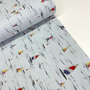 A roll of light gray fabric with a repeating print of small sailboats in red, yellow, blue, and white, alongside abstract black brushstroke lines.