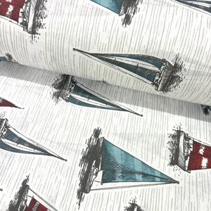 Vintage nautical fabric featuring hand-drawn sailboats with blue, teal and red sails on a textured white background.