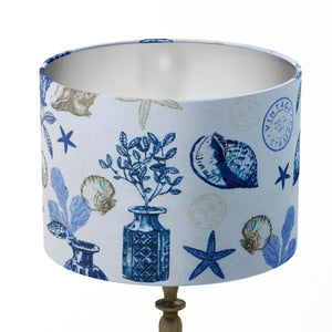 Table lampshade patterned with blue and gold sea shell, starfish, flowers, vase, reefs, vintage stamp on a white background.