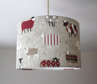 Ceiling lampshade with grey, beige and red sheep pattern on a plain background.