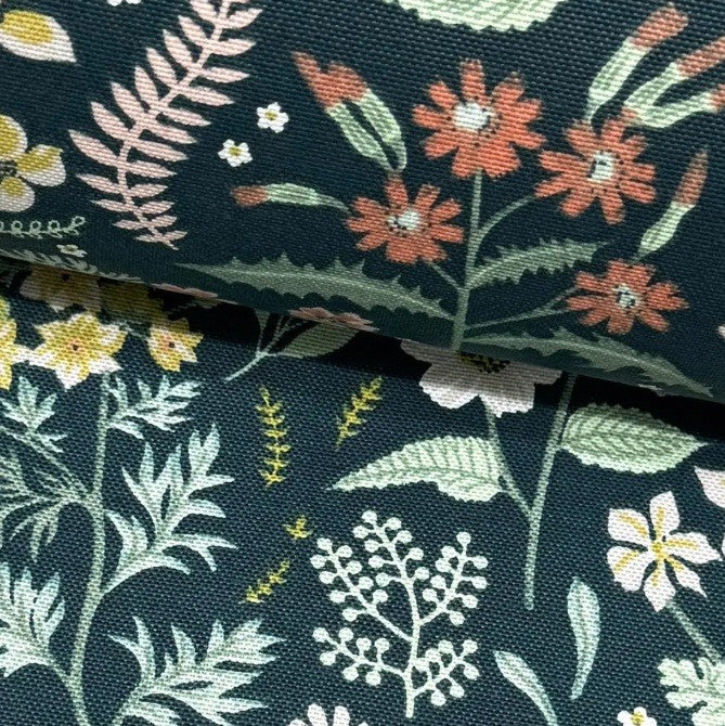 Fabric patterned with coral red and yellow meadow flowers and green leaves on dark green background.